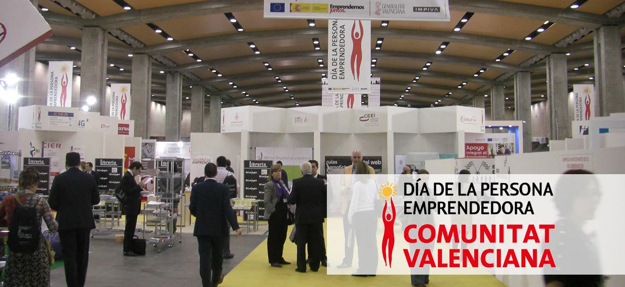 An entrepreneurial fair in Valencia, Spain, with booths and people networking, celebrating the Day of the Entrepreneur in the Valencian Community.