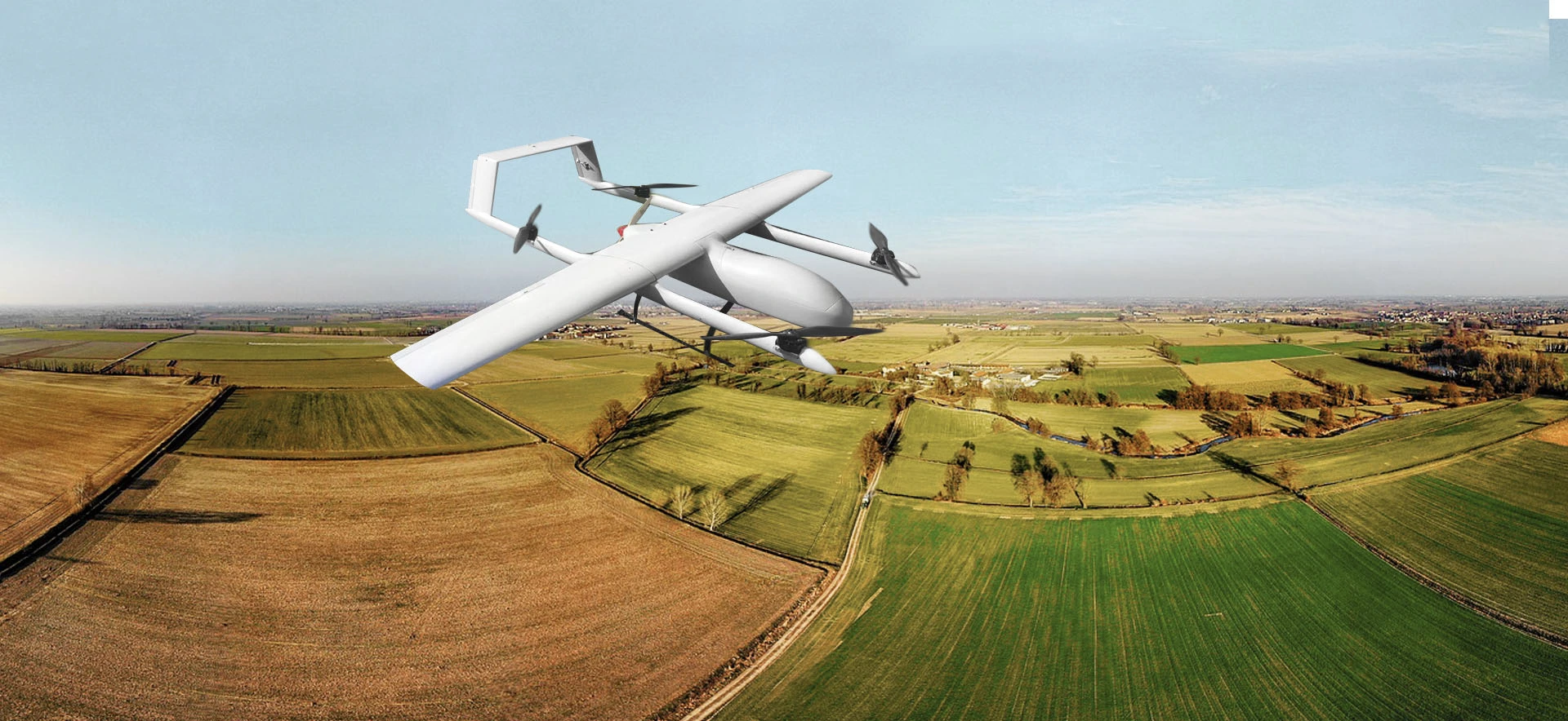 Agricultural drone flying over patchwork fields in rural landscape for precision farming.