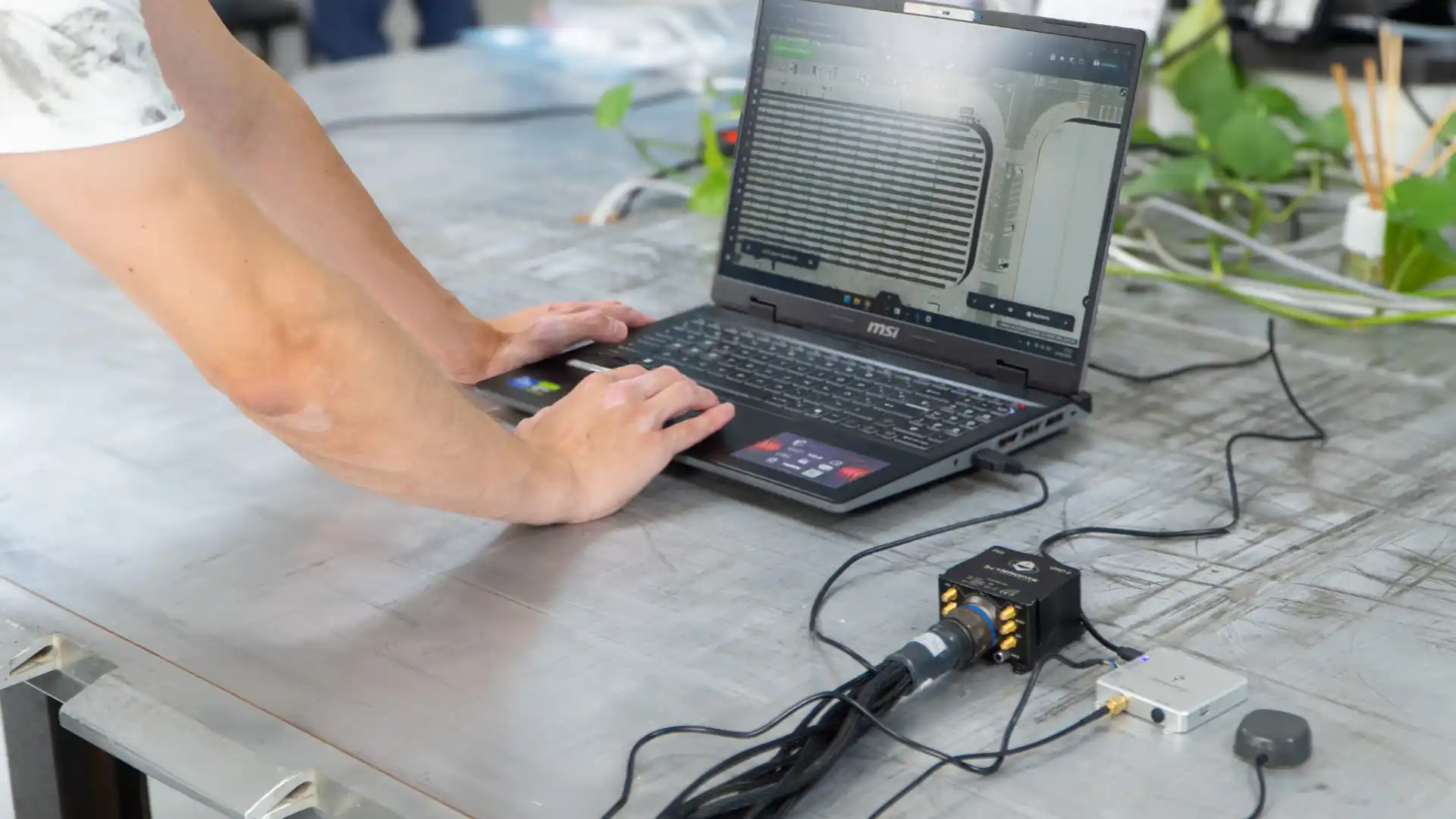 A man is seated at a table, focused on using a laptop computer.