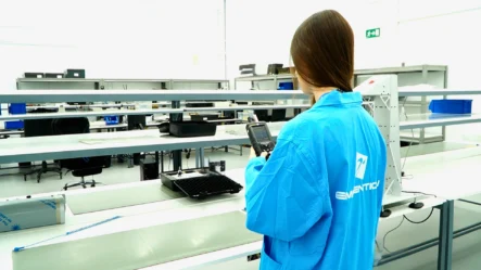 A woman in a blue shirt stands in a laboratory, surrounded by scientific equipment and research materials